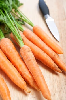 Fresh organic carrots on a wooden chopping board with knife