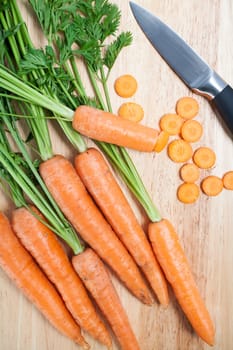 Fresh organic carrots on a wooden chopping board with knife