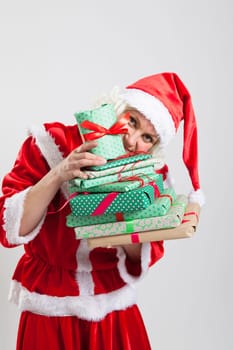 Studio portrait shot of Santa Claus helper elf holding and peering from behind Christmas presents