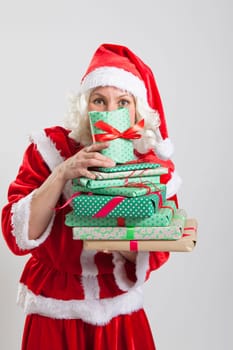 Studio portrait shot of Santa Claus helper elf holding and peering from behind Christmas presents
