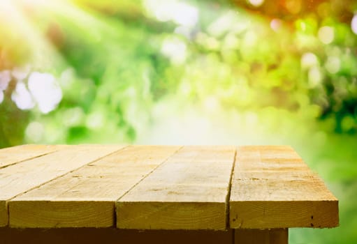 Empty wooden table with garden bokeh for a catering or food background with a country outdoor theme