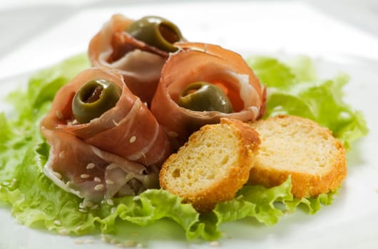 Prosciutto snack with olive and sesame seeds close up