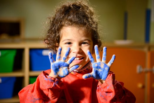 Kids, school and education, happy female child having fun and painting in kindergarten, showing hands to camera