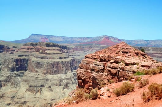 Person standing on top of the rocky knoll at Guano Point on the West Rim of the Grand Canyon.