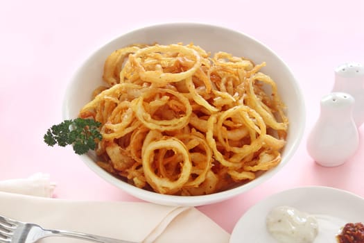 Delicious crispy onion rings fried in batter with tartare sauce ready to serve.