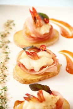 Delicious and delicate shrimps wrapped in bacon on potato slices with a spinach leaf.