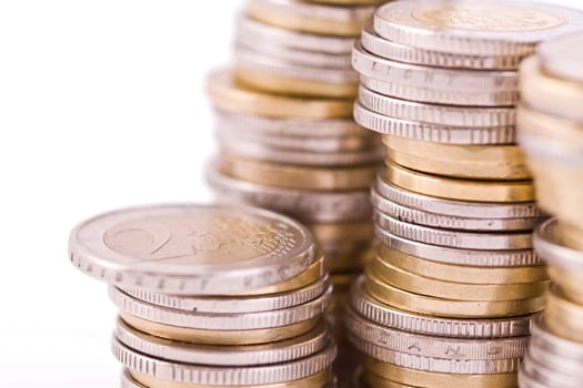 Piles of shiny coins isolated on white, defocused money closeup