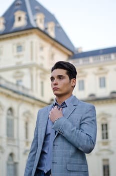Good looking young male model in jacket and tie with elegant palace behind