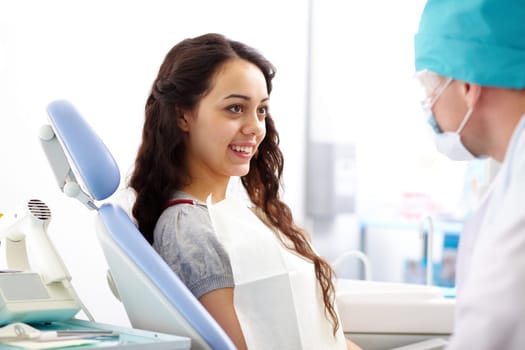 Pretty girl sitting at the dentists and interacting with the doctor