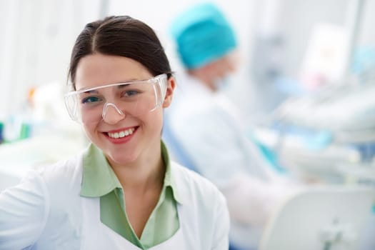 Pretty assistant in protective eyewear looking at camera