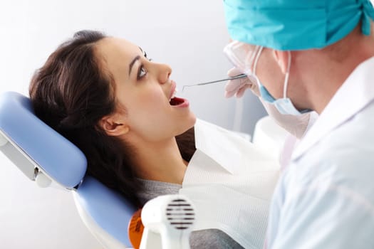 Pretty girl sitting at the dentists and having mouth checkup