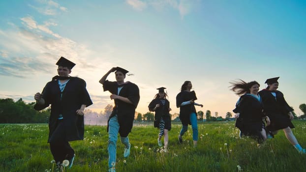 College graduates run off into the sunset in black robes