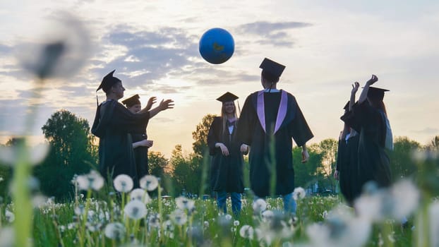 Graduates in costume playing with a ball at sunset