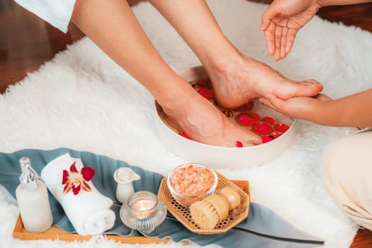 Woman indulges in blissful foot massage at luxurious spa salon while masseur give reflexology therapy in gentle day light ambiance resort or hotel foot spa. Quiescent