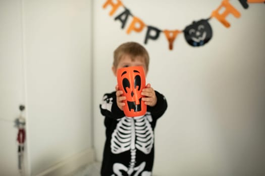 A boy in a skeleton costume and a pumpkin in his hands