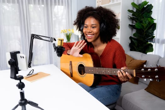 Host channel of beautiful African woman influencer greeting with listeners on broadcast studio. Time slot of music blogger on live social media online. Concept of audio creator. Tastemaker.