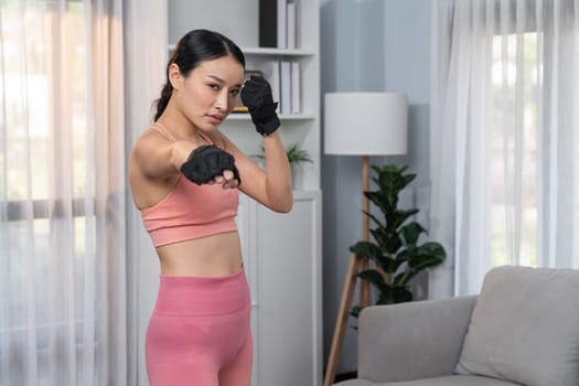 Fit young asian woman portrait in sportswear preparing herself before healthy exercising routine at home. Domestic fitness workout training on living room. Vigorous