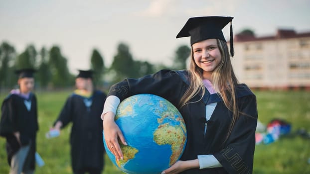 Graduate student girl poses with a globe in a meadow