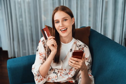 Young happy woman buy product by online shopping at home while ordering items from the internet with credit card online payment system protected by utmost cyber security from online store platform