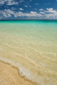 Image of a tropical beach with clear water and blue sky.