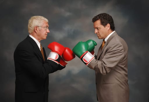 Side view of two business CEO's mock boxing with gloves on.