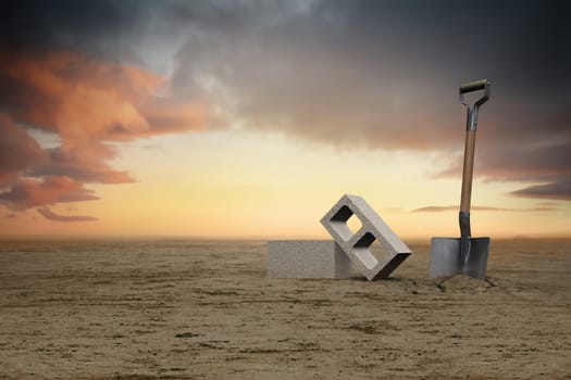 Image of two cement cinder blocks in the sand next to a shovel at sunset.