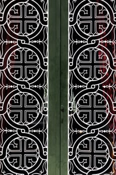 Tangled circles and cross christian religious icon pattern detail on iron church door.