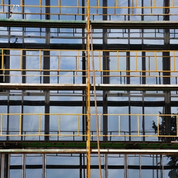Facade windows and iron scaffold detail. Modern glass building under construction.
