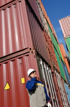 port worker with stacks of shipping containers in background