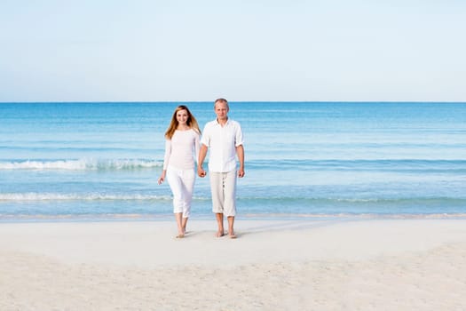 Young couple with man and woman in summer on the beach with blue sky and white clothes