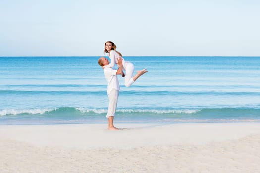 Young couple with man and woman in summer on the beach with blue sky and white clothes