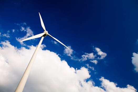 Windmill against a blue sky and clouds, alternative energy source, in horizontal frame