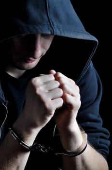 Arrested young men with handcuffs on dark background