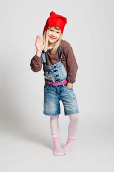 Studio portrait of smiling young girl wearing red Christmas hat and waving
