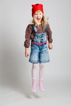 Studio portrait of smiling young girl wearing red Christmas hat and shouting while jumping