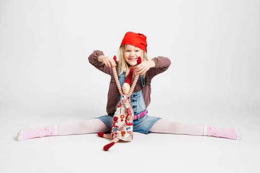Studio portrait of happy smiling young girl holding Christmas elf doll while sitting