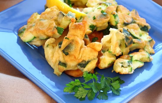 Delicious and delicate freshly fried courgette fritters with parsley ready to serve.