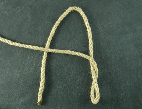 an A of rope lying on a slate table, symbolizing education