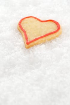 a christmas cookie in figure of a heart lying in the snow