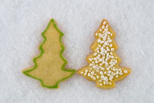 two christmas tree cookies lying next to each other in the snow