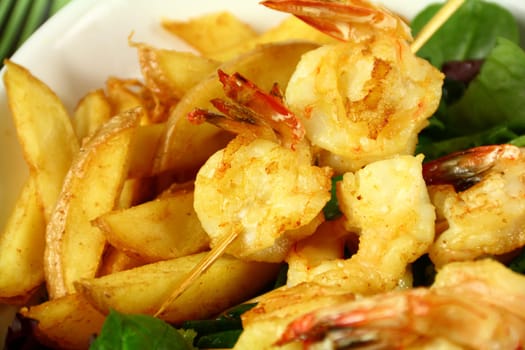 Yummy fried shrimp skewers with chunky chips ready to serve.