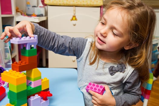 Little girl is playing with building bricks