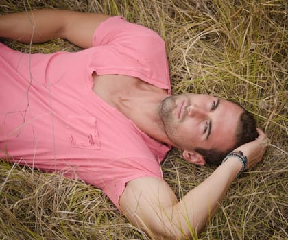 Attractive, fit young man relaxing lying in a field