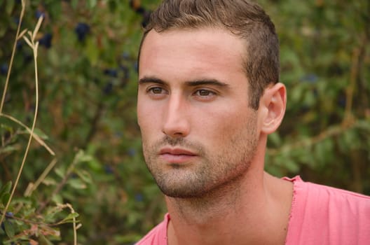 Portrait of handsome guy in front of green plants