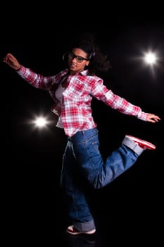 Young African American woman dancing, over black background