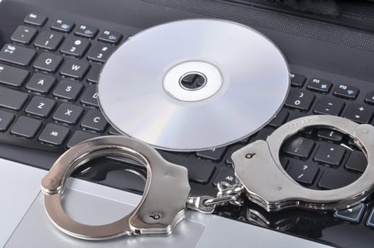 Handcuffs and CD - ROM on laptop