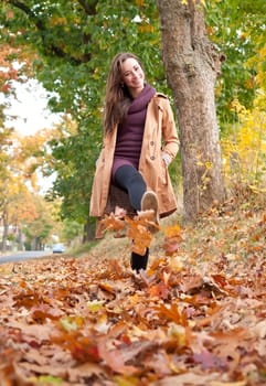 Young woman running in autumn leaves