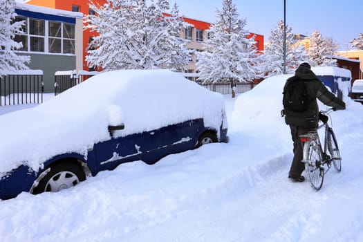 snow-covered car lot in town with cyclist