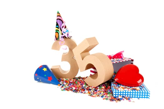 Number of age in a colorful studio setting with paper party hats, a red heart and gifts on a bottom of confettie