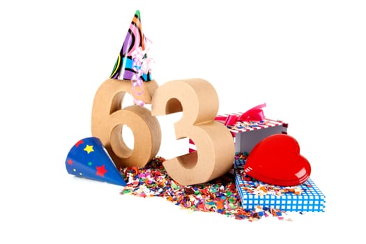 Number of age in a colorful studio setting with paper party hats, a red heart and gifts on a bottom of confettie